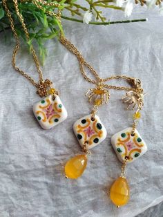 Beautiful set consisting of a Sicilian ceramic necklace and earrings. The necklace is approximately 33 cm long, has a gold-colored stainless steel chain, a yellow swarovski crystal bead, a Sicilian ceramic tile modeled and decorated exclusively by hand, and a beautiful Agate stone drop-shaped pendant. bright yellow color. The earrings have an 18k gold plated galvanized brass hook, ceramic tile and yellow Agate pendant. The tiles are entirely handmade, and some small imperfections are to be consi Handmade Enamel Dangle Jewelry, Unique Necklace With Matching Earrings For Gift, Unique Handmade Ceramic Jewelry, White Ceramic Jewelry For Gifts, White Ceramic Jewelry As A Gift, White Ceramic Jewelry Gift, Yellow Dangle Necklaces As Gifts, Handmade Yellow Jewelry Sets As A Gift, Hand Painted Yellow Jewelry For Gift