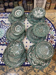 a table topped with lots of green plates on top of a blue and white tile floor