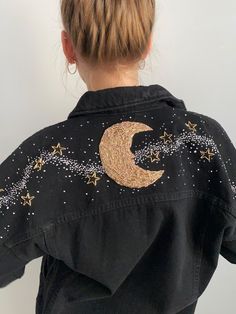 the back of a woman's black jacket with gold stars and a crescent on it