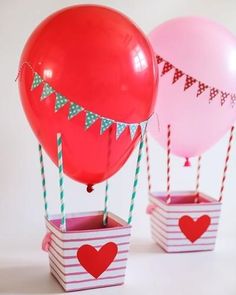 two red and pink balloons are in small boxes with flags on the top, one is filled with hearts