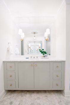 a bathroom with white walls and marble flooring is pictured in this image, there are two lights on either side of the vanity