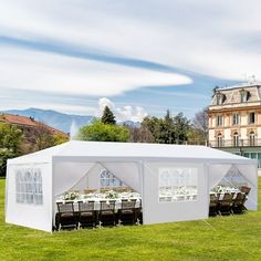 a large white tent set up in the middle of a field with tables and chairs