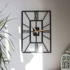 a clock that is on the wall next to a potted plant