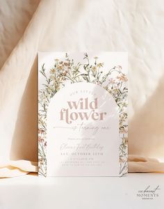 the wild flower wedding card is displayed on a bed