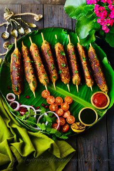 several skewered meats are on a green plate with dipping sauce and garnishes