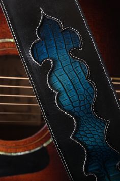 an acoustic guitar strap with a blue design on it