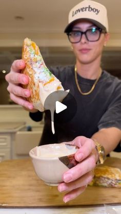 a man holding a sandwich in his hand and dipping it into a bowl with dip