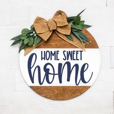 a wooden sign that says home sweet home with a bow on top and greenery around it