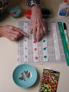 an older woman is doing crafts with her hands on top of the paper and other crafting supplies