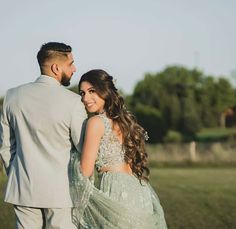 a man and woman standing next to each other in a field