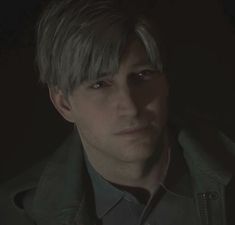 a man with blonde hair wearing a jacket and looking at the camera in a dark room