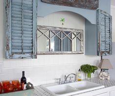 a bathroom sink sitting under a mirror with blue shutters on the window above it