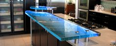 a glass counter top in a kitchen with black cabinets and stainless steel appliances on the wall