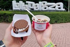 a person holding up an ice cream sundae next to a cup of yogurt