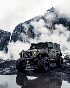 a jeep is parked in front of a mountain with steam coming out of the tires