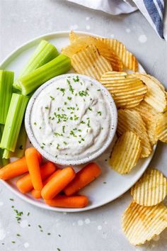 a plate with chips, celery, carrots and dip