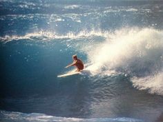 a man riding a wave on top of a surfboard in the ocean with blue water