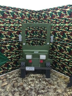 a toy jeep is sitting in front of a wall covered with camo print fabric