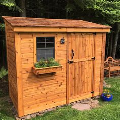 a small wooden shed with plants in the window