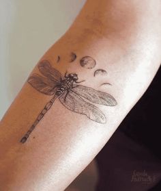 a woman's arm with a dragonfly tattoo on it