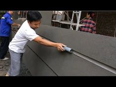 a man is using a hand sander to paint the side of a gray wall