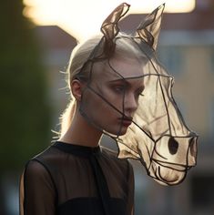 a woman in sheer clothing with a horse head on her head and veil over her face