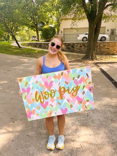 a girl in sunglasses holding up a sign that says we love you with hearts on it