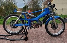 a blue motorcycle parked on top of a gravel road