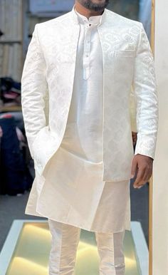 a man in a white outfit standing on a runway