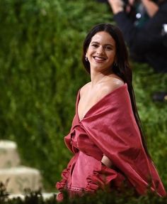 a woman in a red dress is smiling at the camera