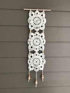 three crocheted doily hanging on the side of a house with wooden pegs