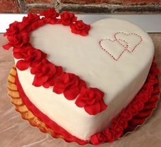 a heart shaped cake with red flowers on it