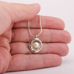 This "Aruba" pearl pendant necklace is handmade of 925 Sterling Silver. It has been hand crafted and cast in pure 92.5% solid silver in my workshop using a technique called water casting. I melt silver and pour the molten silver into cold water! The resulting organic shape creates a cup that imitates nature in a beautiful way. Finally, the lovely cultured pearl is set inside the cup to create this unique pendant.Pearl color: white Pendant size: approx 3/4 inch (20 mm) diameter The pendant hangs Luxury Sterling Silver Pearl Drop Necklace, Silver Necklace With Pearl, Silver Pendant Necklace Unique, Silver Pearl Necklace, Silver Snake Chain, Buddhist Art, Pearl Pendant Necklace, Unique Pendant, Pearl Color