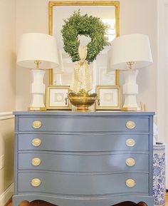 a blue dresser with two lamps and a wreath on top