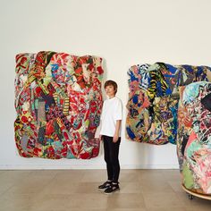 a woman standing in front of two large pieces of art