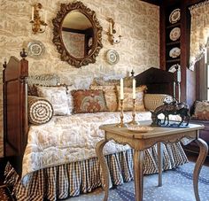 a bed room with a neatly made bed next to a dresser and mirror on the wall