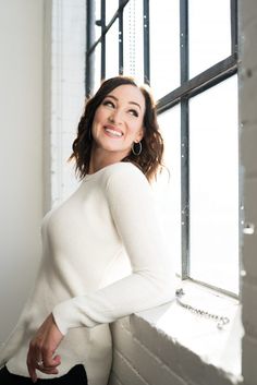 a smiling woman leaning against a window sill