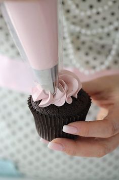 a cupcake being decorated with pink icing