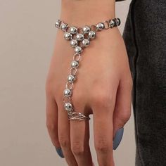 a woman's hand wearing a silver bracelet with balls and chains attached to it