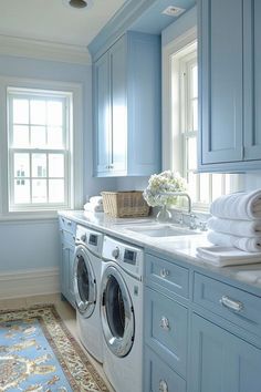 a washer and dryer in a blue laundry room with lots of cabinetry