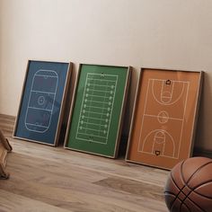 three framed sports pictures sitting on top of a hard wood floor next to a basketball