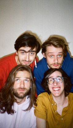 four men with long hair and glasses posing for a photo