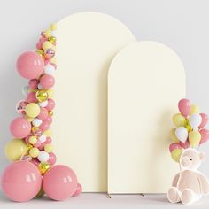 a teddy bear sitting next to balloons and a white arch with a pink balloon garland on it