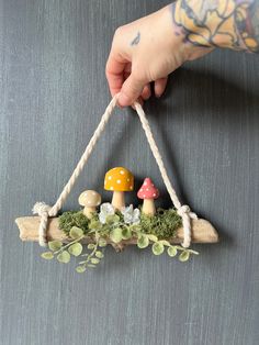 a person holding a piece of wood with mushrooms on it and plants growing out of it