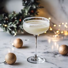 a glass filled with a drink sitting on top of a table next to christmas decorations