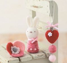 two small stuffed animals sitting on top of a wooden bench next to a heart shaped keychain