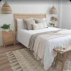 a bed with white linens and pillows in a bedroom next to a wooden table