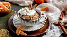 a bowl filled with food sitting on top of a wooden plate next to an orange slice