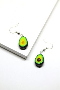 These avocado dangle earrings are the cutest two yummy green slices! These earring charms are about half and inch tall, hard plastic and are made with hypoallergenic silver plated earring hooks. All of our charms are 100% hand sculpted, hand painted, and sealed with a clear vanish to keep it safe. These earring are for pierced ears and are very light to wear. Our items are not factory made, so no one item is a complete replica - expect a little handmade charm and love! Green Fruit Design Earrings As Gift, Gift Green Earrings With Fruit Design, Green Fruit Design Earrings Gift, Green Fruit Design Earrings For Gifts, Bff Necklaces For 2 Avocado, Avocado Necklace, Avocado Keychain, Food For Health, Avocado Earrings