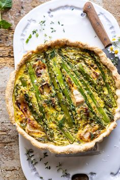 a quiche with asparagus and cheese on a plate next to a knife